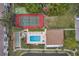 Top-down aerial view of a pool, shuffleboard, and tennis court surrounded by lush landscaping at 8158 Eagles Park N Dr, St Petersburg, FL 33709