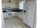 White kitchen with modern appliances, including a stove, microwave, refrigerator, and tiled flooring at 8158 Eagles Park N Dr, St Petersburg, FL 33709