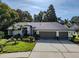 Stunning single-story home featuring a three-car garage, beautiful landscaping, and a charming front yard at 910 Kingscote Ct, Safety Harbor, FL 34695