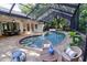 Screened-in kidney-shaped pool with brick pavers, a spillover spa, and lounge seating at 910 Kingscote Ct, Safety Harbor, FL 34695