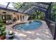 Screened-in kidney-shaped pool with brick pavers and a spillover spa surrounded by lush landscaping at 910 Kingscote Ct, Safety Harbor, FL 34695