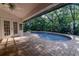 Screened in pool area with brick pavers, offering privacy and surrounded by lush landscaping at 910 Kingscote Ct, Safety Harbor, FL 34695
