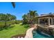 Expansive backyard with lush lawn, mature trees, and a pool with waterfall and spa, offering a serene outdoor oasis at 10930 Spring St, Largo, FL 33774