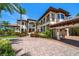 Elegant Mediterranean-style home showcasing a porte-cochere, lush landscaping, and a brick circular driveway at 10930 Spring St, Largo, FL 33774