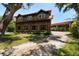 Beautifully designed barn-style home with a gravel driveway, mature trees, and a separate covered structure at 10930 Spring St, Largo, FL 33774