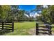 Expansive fenced pasture surrounded by mature trees under a clear blue sky at 10930 Spring St, Largo, FL 33774