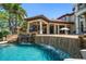 Luxury home featuring a stunning pool with rock waterfall, outdoor kitchen, and covered patio area at 10930 Spring St, Largo, FL 33774