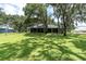Spacious backyard view of the home's screened-in porch with mature trees offering shade and a lush lawn at 11008 Nest Ct, Odessa, FL 33556