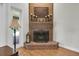 Classic brick fireplace with wood mantle, decorative metal screen, and light wood flooring at 11008 Nest Ct, Odessa, FL 33556