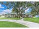 Charming home with a well-manicured lawn, a circular driveway, and stately mature trees at 11008 Nest Ct, Odessa, FL 33556