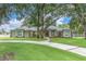 Beautiful single-story home featuring mature trees, a curved driveway, and a well-manicured lawn at 11008 Nest Ct, Odessa, FL 33556