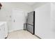 Utility area with stainless steel refrigerator, white door, tiled floor, and extra storage space at 11008 Nest Ct, Odessa, FL 33556