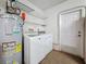Functional laundry room with a washer, dryer, water heater, and shelving at 11362 Heritage Way, Largo, FL 33778