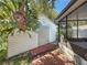 Exterior of the white shed with brick base and mature landscaping adjacent to screened lanai at 11362 Heritage Way, Largo, FL 33778