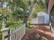 Outdoor shed with a white picket fence and mature tree in the landscaped backyard at 11362 Heritage Way, Largo, FL 33778