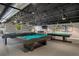 Spacious billiards room with multiple pool tables, shuffleboard table, and comfortable seating at 11439 Golf Round Dr, New Port Richey, FL 34654