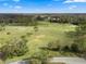 Scenic aerial view of the lush green golf course with mature trees, a pond and distant homes on a clear day at 11439 Golf Round Dr, New Port Richey, FL 34654