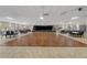 Spacious recreation room featuring hardwood dance floor, tables, chairs, stage, and window blinds at 11439 Golf Round Dr, New Port Richey, FL 34654