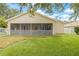 Spacious backyard featuring a screened porch, lush green grass, and white picket fence at 11830 Autumn Creek Dr, Riverview, FL 33569