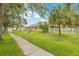 Landscaped front yard with mature trees, green grass, and sidewalk leading to home's entrance at 11830 Autumn Creek Dr, Riverview, FL 33569