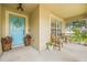 Inviting front porch with wooden chairs, a bright blue front door, and decorative plants at 11830 Autumn Creek Dr, Riverview, FL 33569