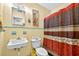 Bathroom with yellow tile and retro fixtures includes a toilet, sink and red patterned shower curtain at 1213 Cuttingin Pl, Tampa, FL 33612