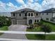 Aerial view of a beautifully landscaped two-story home with a three-car garage and solar panels at 12821 Satin Lily Dr, Riverview, FL 33579