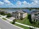 Aerial shot of a solar-paneled two-story house with well-manicured lawn situated by a tranquil lake at 12821 Satin Lily Dr, Riverview, FL 33579