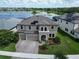 An aerial shot of a modern two-story home with a three-car garage and solar panels overlooking the lake at 12821 Satin Lily Dr, Riverview, FL 33579