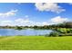 Scenic lake view with lush green lawn, beautiful blue skies, and scattered cumulus clouds at 12821 Satin Lily Dr, Riverview, FL 33579