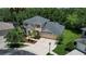 Aerial view of home surrounded by mature trees, a spacious driveway, and a large three-car garage at 16102 Colchester Palms Dr, Tampa, FL 33647