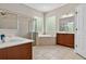 Bathroom featuring dual vanities, walk-in shower, soaking tub, and neutral tile flooring at 16102 Colchester Palms Dr, Tampa, FL 33647
