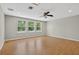 Large bonus room with three windows, wood-look floors, and ceiling fan at 16102 Colchester Palms Dr, Tampa, FL 33647