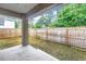 A concrete backyard patio with a wooden fence and green foliage in the background at 1717 Preston S St, St Petersburg, FL 33712