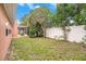 Fenced backyard with green grass, mature trees, and enclosed patio provides a private outdoor space at 1741 Font Ln, Holiday, FL 34691
