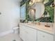 This bathroom features a round mirror, marble countertops, and tropical themed wallpaper at 17715 Wall Cir, Redington Shores, FL 33708