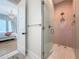 Modern bathroom with pink tiled shower and a view to the bedroom with a chandelier at 17715 Wall Cir, Redington Shores, FL 33708