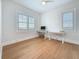 Bright bedroom features light wood floors, a ceiling fan, and abundant natural light from two windows with shutters at 17715 Wall Cir, Redington Shores, FL 33708