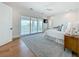 Bright bedroom with water views and large sliding glass doors to a balcony, light wood floors, and ceiling fan at 17715 Wall Cir, Redington Shores, FL 33708