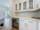 Elegant kitchen featuring white cabinetry, wine cooler, quartz countertops and herringbone tile backsplash at 17715 Wall Cir, Redington Shores, FL 33708