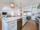 Kitchen island with seating, stainless steel appliances, pendant lights, and white cabinetry for ample storage at 17715 Wall Cir, Redington Shores, FL 33708