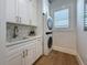 Bright laundry room featuring white cabinets, patterned backsplash, and modern stackable washer and dryer at 17715 Wall Cir, Redington Shores, FL 33708
