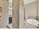 Luxurious bathroom featuring stone tile walls, walk-in shower and soaking tub at 2120 Gwynhurst Blvd, Wesley Chapel, FL 33543