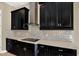 Close-up of a kitchen featuring black cabinets, light countertops and brick backsplash at 2120 Gwynhurst Blvd, Wesley Chapel, FL 33543