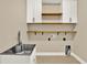 Bright laundry room with white cabinets, wood shelving, stainless steel sink, and neutral paint at 2120 Gwynhurst Blvd, Wesley Chapel, FL 33543