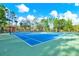 Well-maintained tennis court with bright blue surface and surrounded by lush greenery at 2120 Gwynhurst Blvd, Wesley Chapel, FL 33543