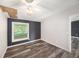 Bedroom featuring wood-look flooring, an accent wall, a ceiling fan, and a window with natural light at 2121 Odessa Gardens Ln, Odessa, FL 33556