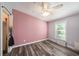 This bedroom features woodgrain vinyl floors, a closet, ceiling fan and window at 2121 Odessa Gardens Ln, Odessa, FL 33556