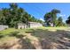 Exterior shot featuring lush lawn, shed, and cozy single-story home with a wooded backdrop at 2121 Odessa Gardens Ln, Odessa, FL 33556