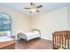 Well-lit bedroom featuring hardwood floors, ceiling fan, and space for a crib near the window at 2504 Oak Landing Dr, Brandon, FL 33511